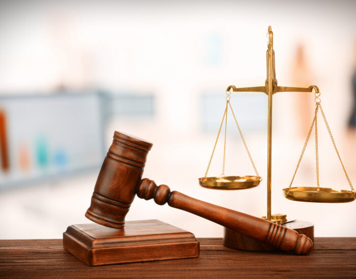 Judge's gavel and scales on blurred computers background